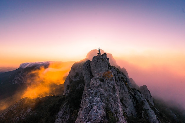 Photo gratuite vue aérienne d'une femme avec les mains sur le sommet de la montagne au coucher du soleil