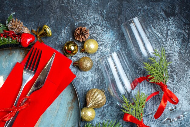 Vue Aérienne De Gobelets En Verre Avec Des Couverts En Ruban Rouge Sur Une Assiette Bleue Et Des Accessoires De Décoration De Branches De Sapin Sur Fond Sombre