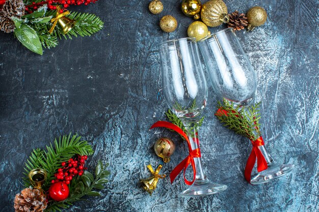 Vue aérienne de gobelets en verre tombés avec ruban rouge et accessoires de décoration cônes de conifères sur fond sombre