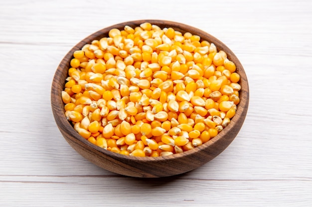 Vue aérienne de grains de maïs dans un bol marron sur fond blanc