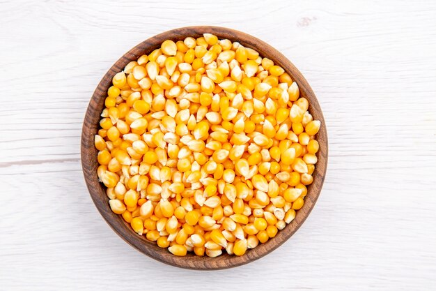 Vue aérienne de grains de maïs frais dans un bol marron sur fond blanc