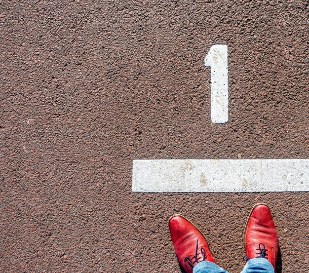 Vue aérienne d'un homme en chaussures rouges debout devant une ligne numéro "1"