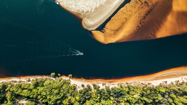 Photo gratuite vue aérienne d'un hors-bord naviguant le long de la rivière sur la rive du sable doré