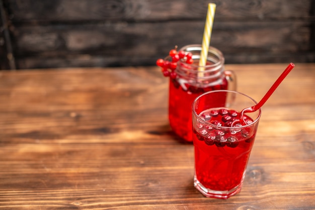 Vue aérienne de jus de groseille frais biologique naturel dans un verre et une bouteille servie avec des tubes sur le côté gauche sur une table en bois