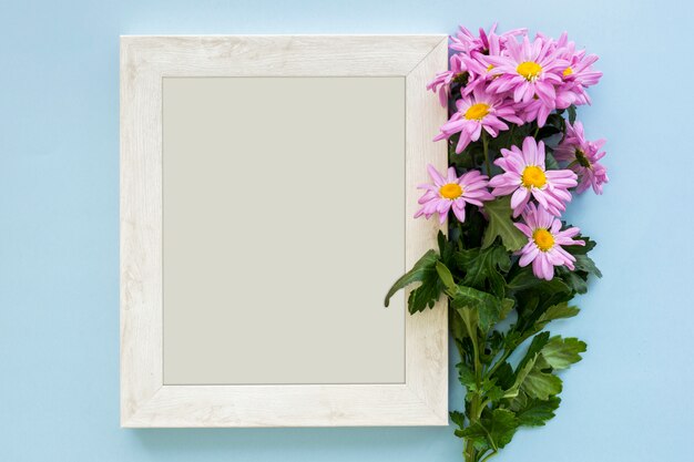 Vue aérienne d&#39;une marguerite pourpre fleurs et cadre photo blanc sur fond bleu