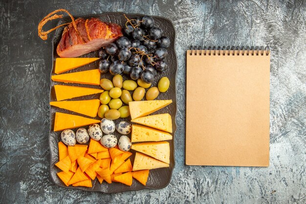 Vue aérienne de la meilleure collation délicieuse pour le vin sur un plateau marron et un cahier sur fond de glace