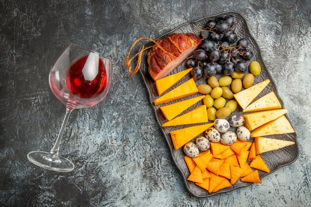 Vue aérienne de la meilleure collation savoureuse sur un plateau marron et un verre de vin tombé sur fond de glace