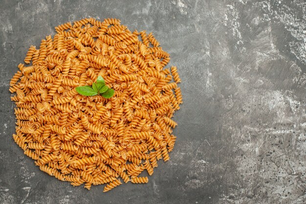 Vue aérienne de pâtes italiennes crues avec du vert disposé en cercle sur le côté droit sur fond gris