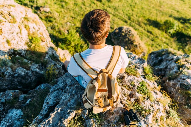 Vue aérienne d&#39;un randonneur mâle avec sac à dos assis sur le rocher