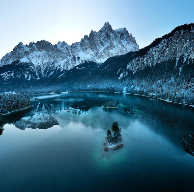 Photo gratuite vue aérienne de la rivière eibsee gelée entourée d'arbres couverts de neige en bavière, allemagne