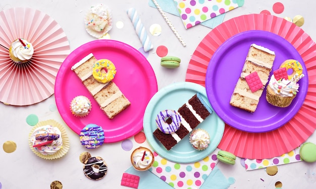 Une vue aérienne de la table décorée de couleurs vives avec de délicieux morceaux de gâteau