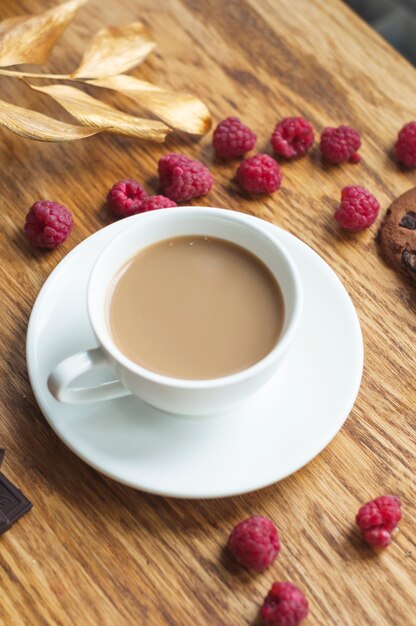 Vue aérienne, de, tasse à café, sur, soucoupe, à, framboises fraîches, sur, table bois