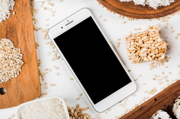 Photo gratuite vue aérienne d'un téléphone portable entouré d'une variété de riz soufflé et non cuit