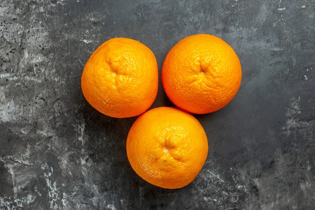 Vue aérienne de trois oranges fraîches biologiques naturelles sur fond sombre