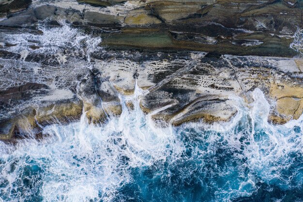 Vue aérienne des vagues du Pacifique déferlant sur un éperon rocheux le long de la côte de l'île de Biri