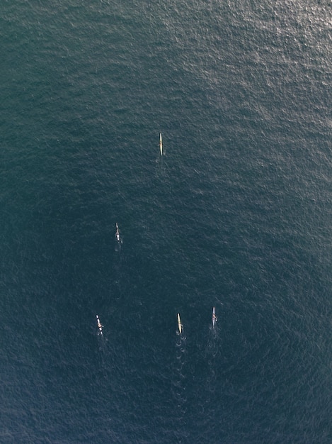 Vue aérienne verticale de personnes dans des bateaux de kayak pagayant dans une eau calme et claire de l'océan