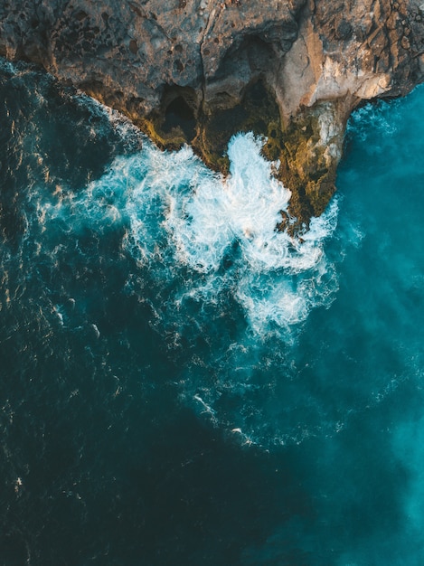 Vue aérienne verticale des vagues de la mer frappant la falaise