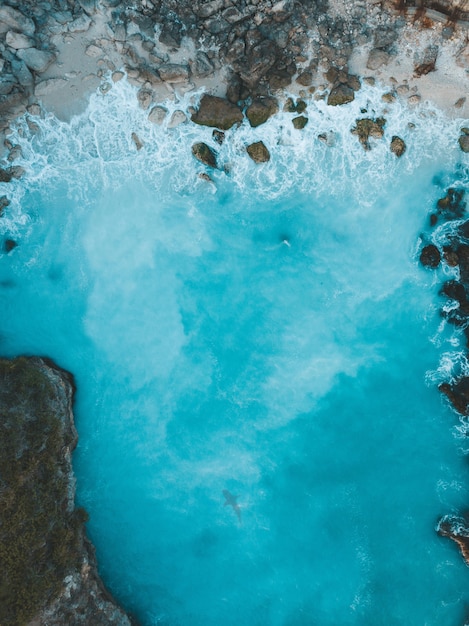 Vue aérienne verticale des vagues de la mer frappant les rochers sur la rive