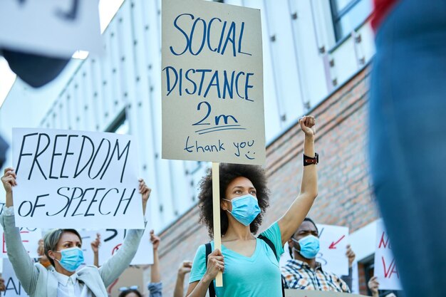 Vue en angle bas d'une femme afro-américaine avec le poing levé participant à des manifestations pendant l'épidémie de coronavirus