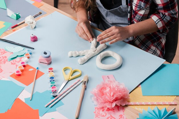 Vue d&#39;angle élevé de l&#39;artiste féminine faisant la lettre avec de l&#39;argile blanche sur le bureau