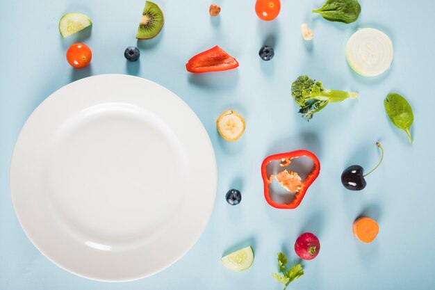 Vue d&#39;angle élevé de légumes et assiette sur fond bleu