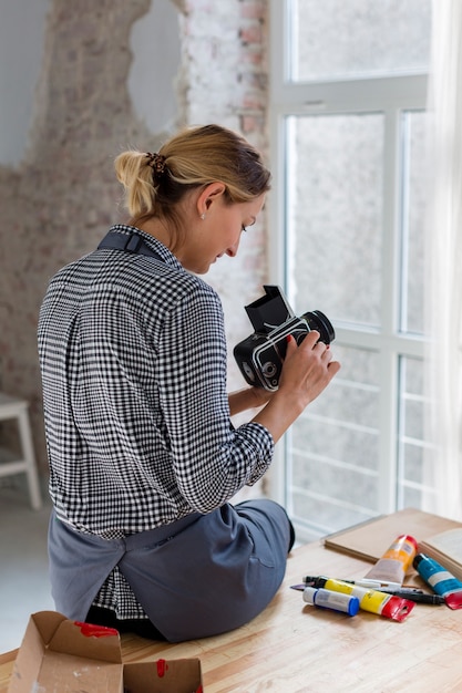 Vue arrière de l'artiste en tablier tenant l'appareil photo