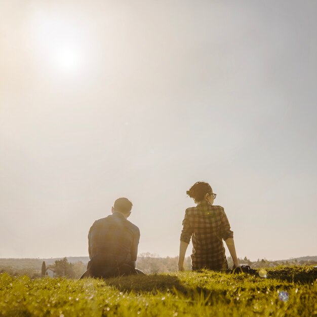 Vue arrière de couple détendu assis sur la pelouse