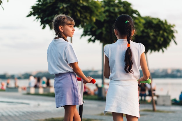 Vue arrière de deux filles avec un scooter