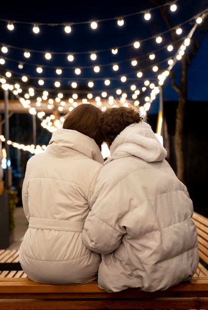 Vue arrière du couple debout à l'extérieur avec des lumières