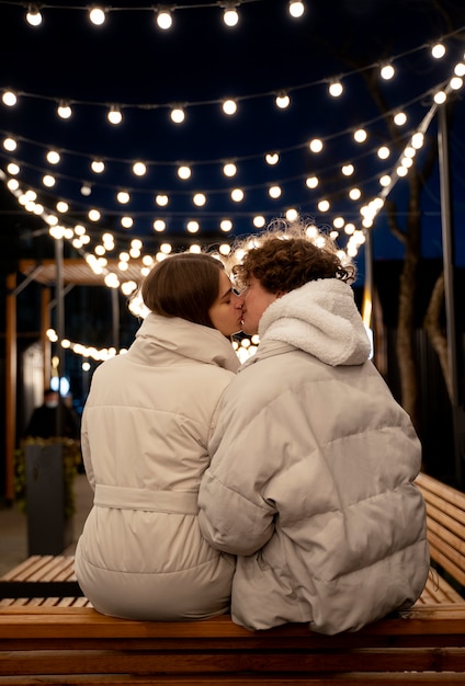 Vue arrière du couple debout à l'extérieur avec des lumières