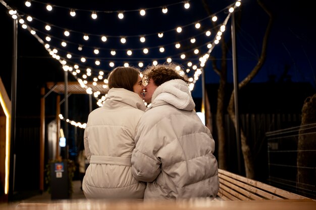 Vue arrière du couple debout à l'extérieur avec des lumières