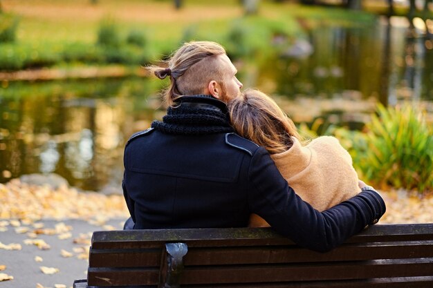 Vue arrière du couple est assis sur un banc dans un parc en automne.