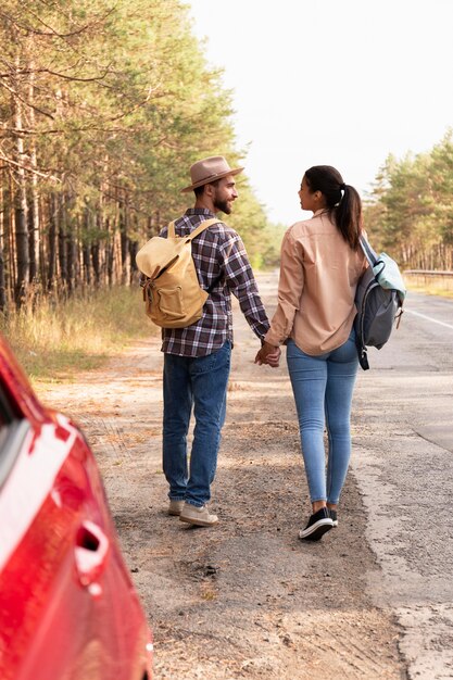 Vue arrière du couple prenant une promenade avec leurs sacs à dos sur