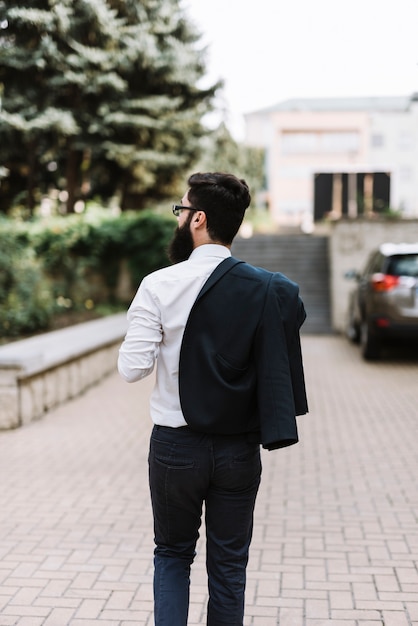 Vue arrière du jeune homme d&#39;affaires avec un manteau sur son épaule