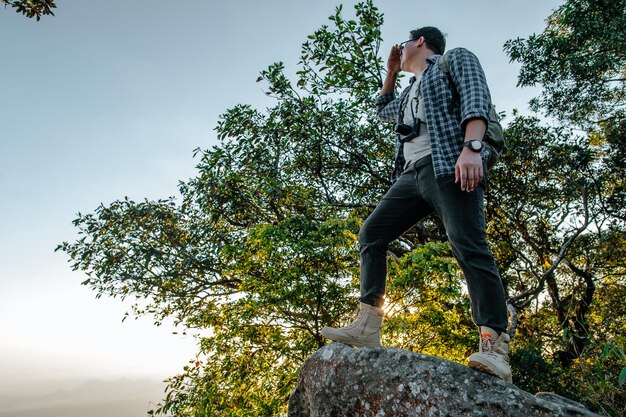 Vue arrière du jeune homme de randonnée asiatique debout au point de vue et à la belle vue avec heureux sur la montagne de pointe et l'espace de copie du rayon de soleil