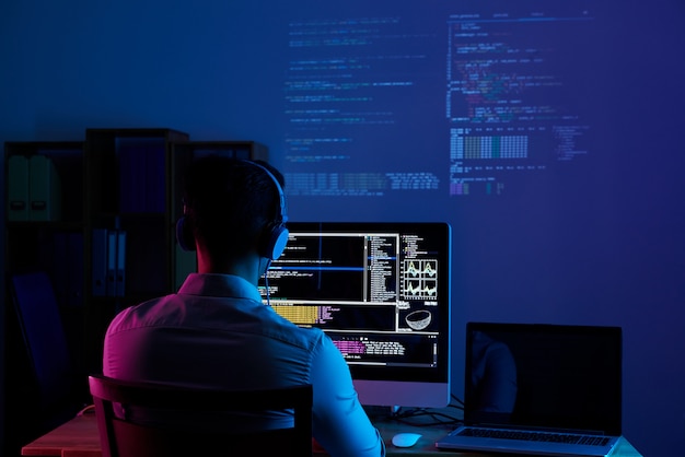 Vue arrière du programmeur travaillant toute la nuit