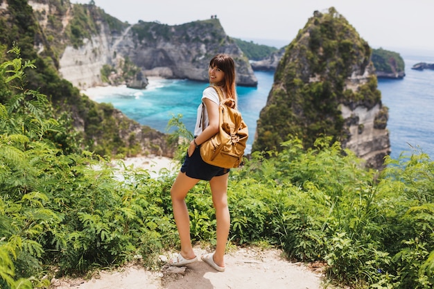 Vue arrière du voyage femme debout sur les falaises et la plage tropicale