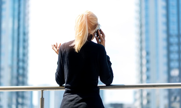 Vue arrière de la femme d'affaires plus âgée à l'extérieur sur un appel téléphonique