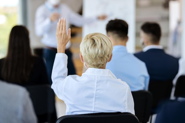 Vue arrière d'une femme d'affaires posant une question sur un séminaire dans la salle du conseil