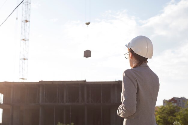 Vue arrière, de, femme architecte, porter, hart, chapeau, regarder, construction