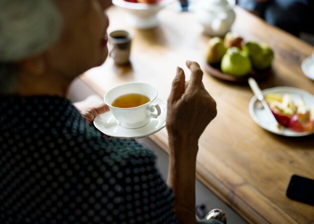 Vue arrière d&#39;une femme asiatique senior tenant une tasse de thé en discutant avec des amis