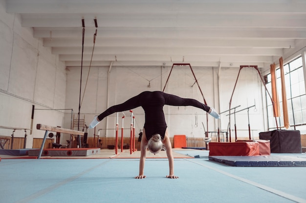 Vue arrière femme blonde exerçant pour les jeux olympiques de gymnastique