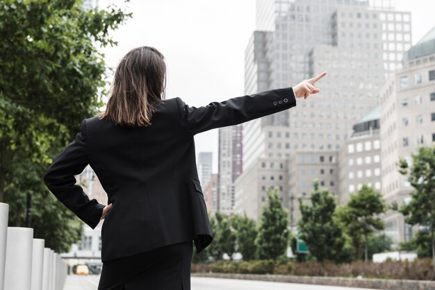 Vue arrière femme en costume pointant vers le haut