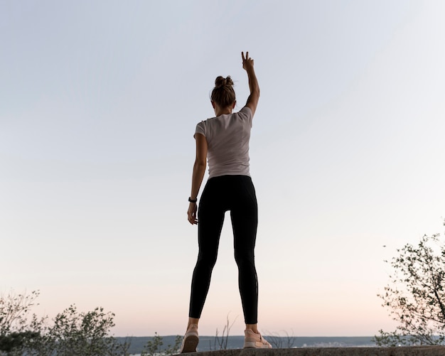 Vue arrière femme debout de manière victorieuse