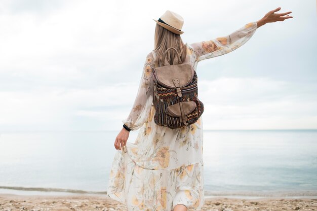 Vue arrière femme élégante avec sac à dos, profitant de voyage