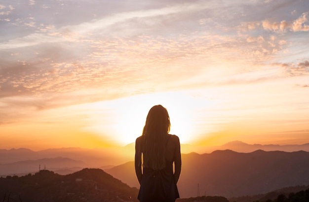 Vue arrière de la femme faisant du yoga tout en regardant le coucher du soleil