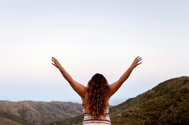 Vue arrière de la femme insouciante à l'extérieur avec les mains