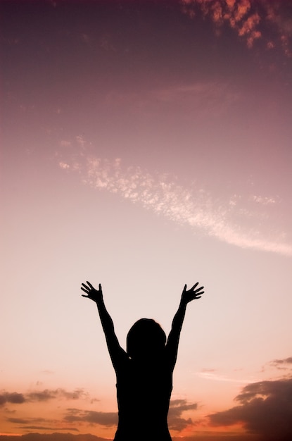 Vue arrière de la femme avec les mains levées en regardant le ciel