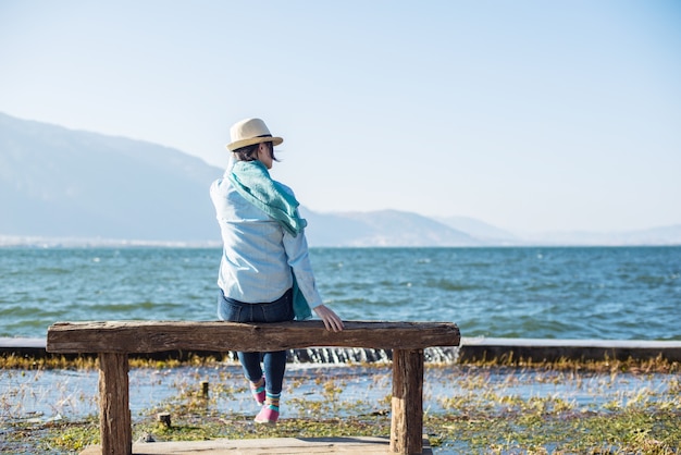 Vue arrière de la femme paisible assis sur un banc en bois