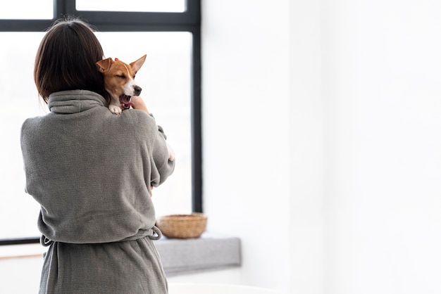 Photo gratuite vue arrière d'une femme en peignoir tenant son chien